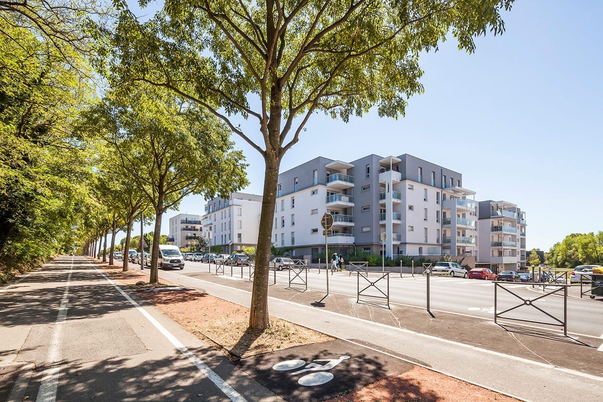 Photographie d'architecture et immeubles du clos vus depuis une piste cyclable arborée