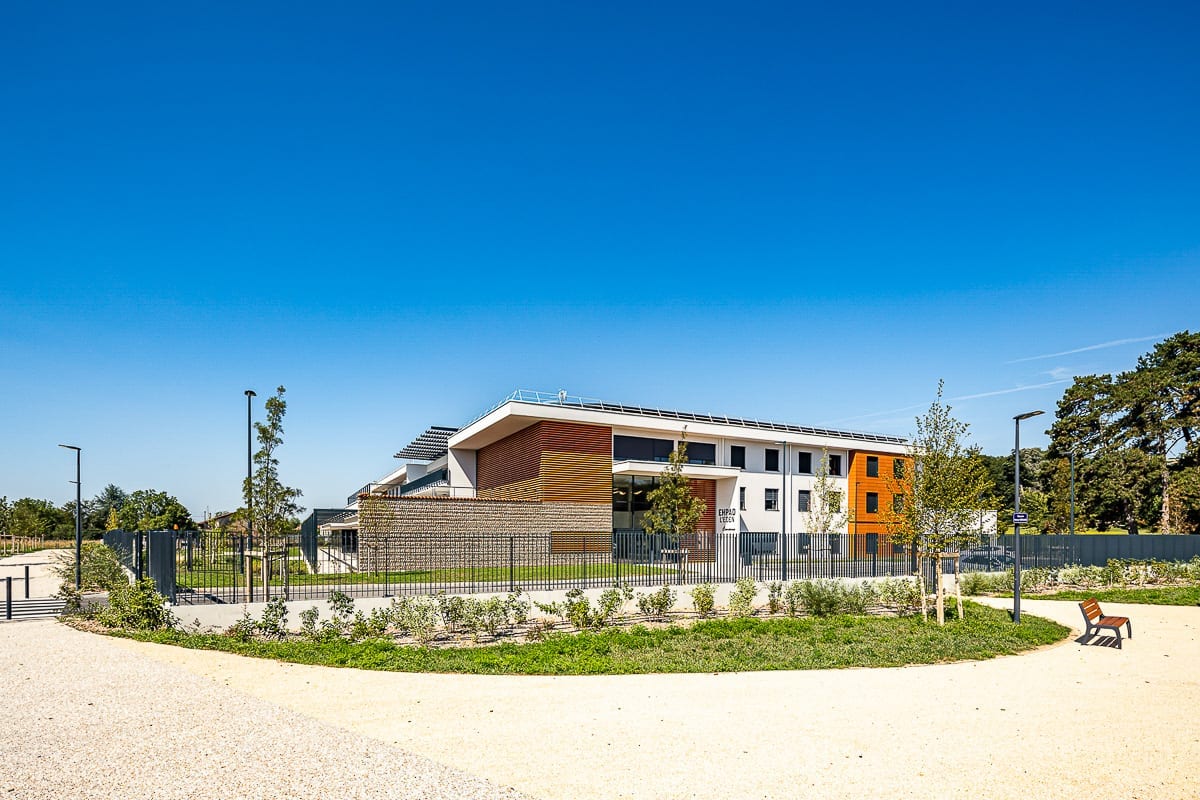 Photographie d'architecture d'une petite place baignée de lumière devant l'ehpad