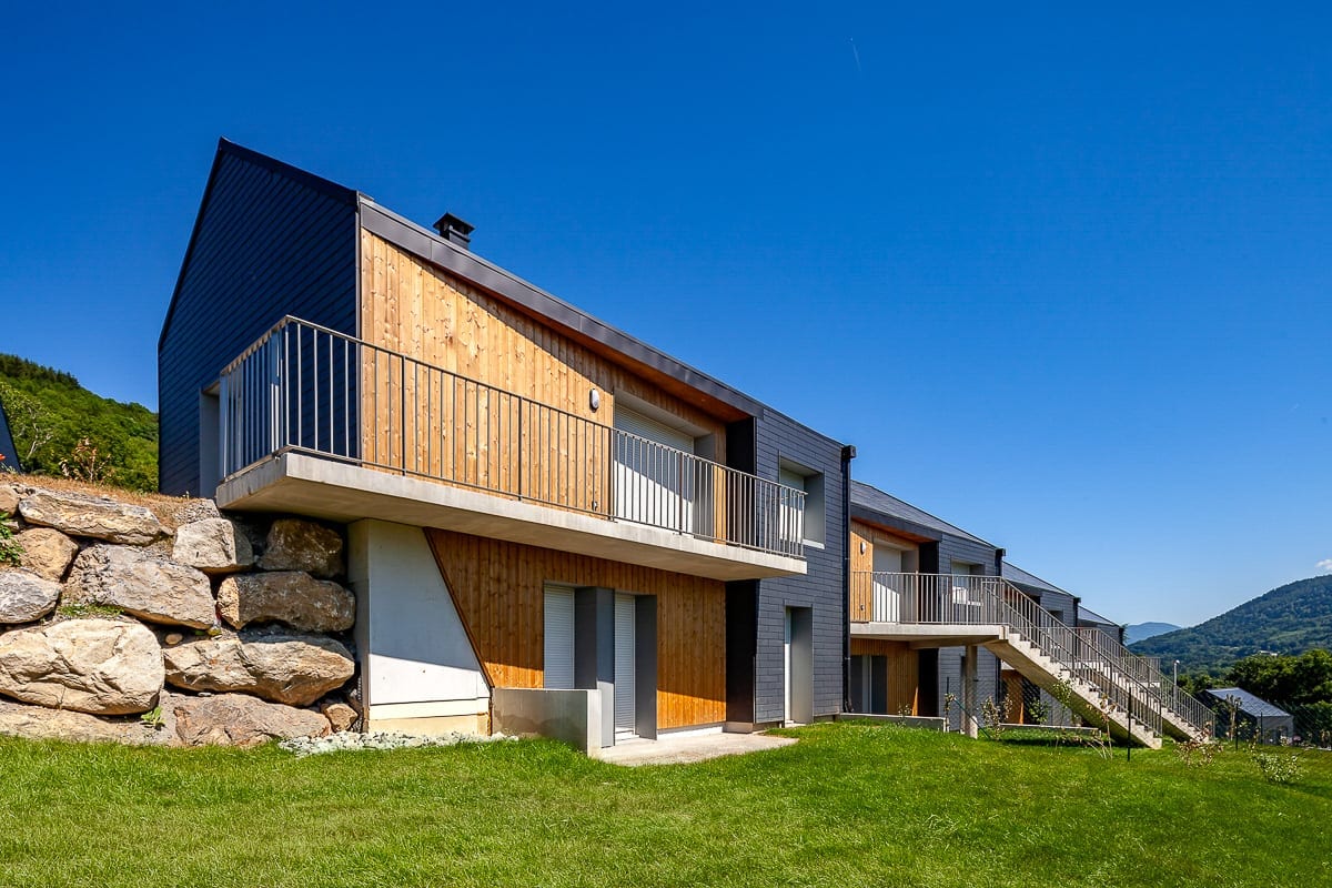 Photographie d'architecture de maisons mitoyennes avec grosses pierres depuis leur jardin