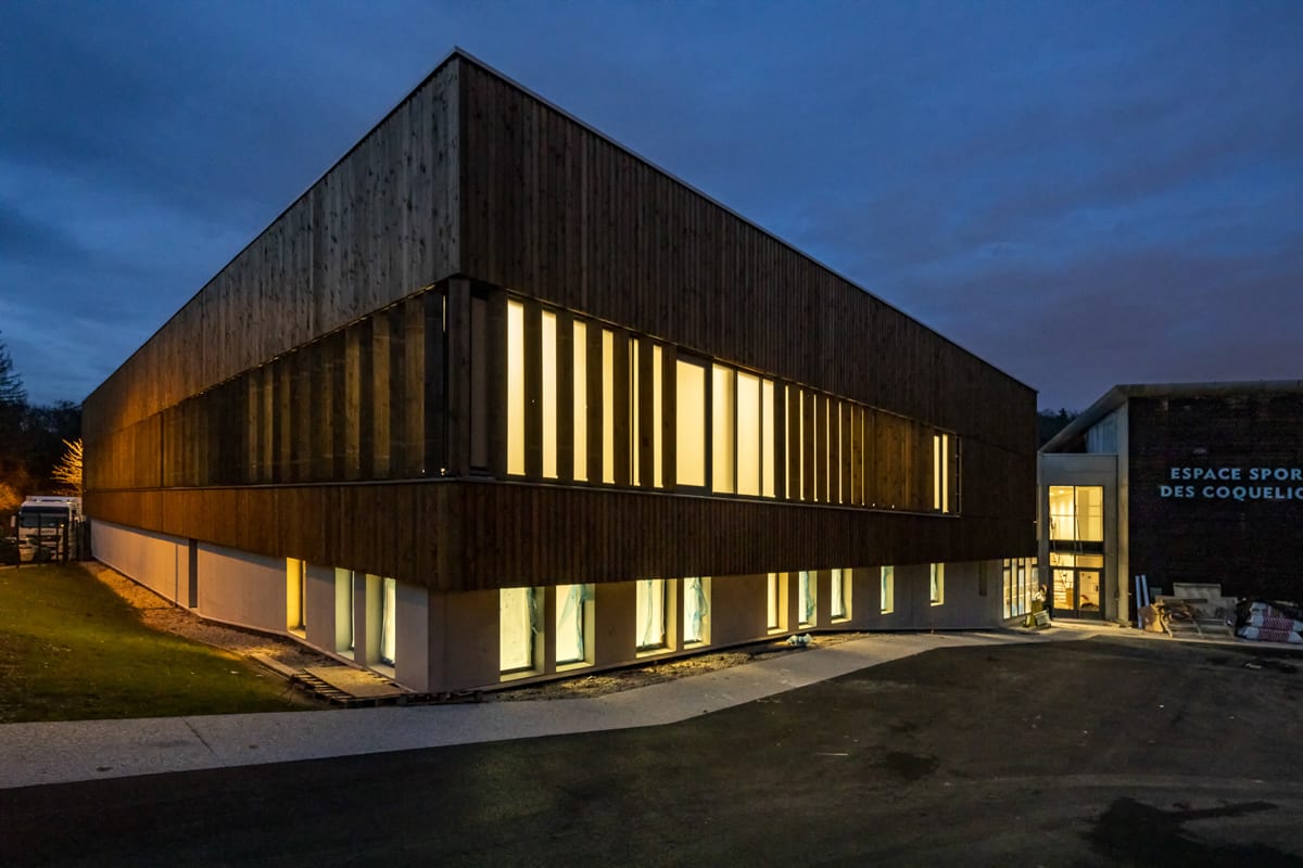 Vue extérieure de nuit d'un gymnase éclairé de l'intérieur