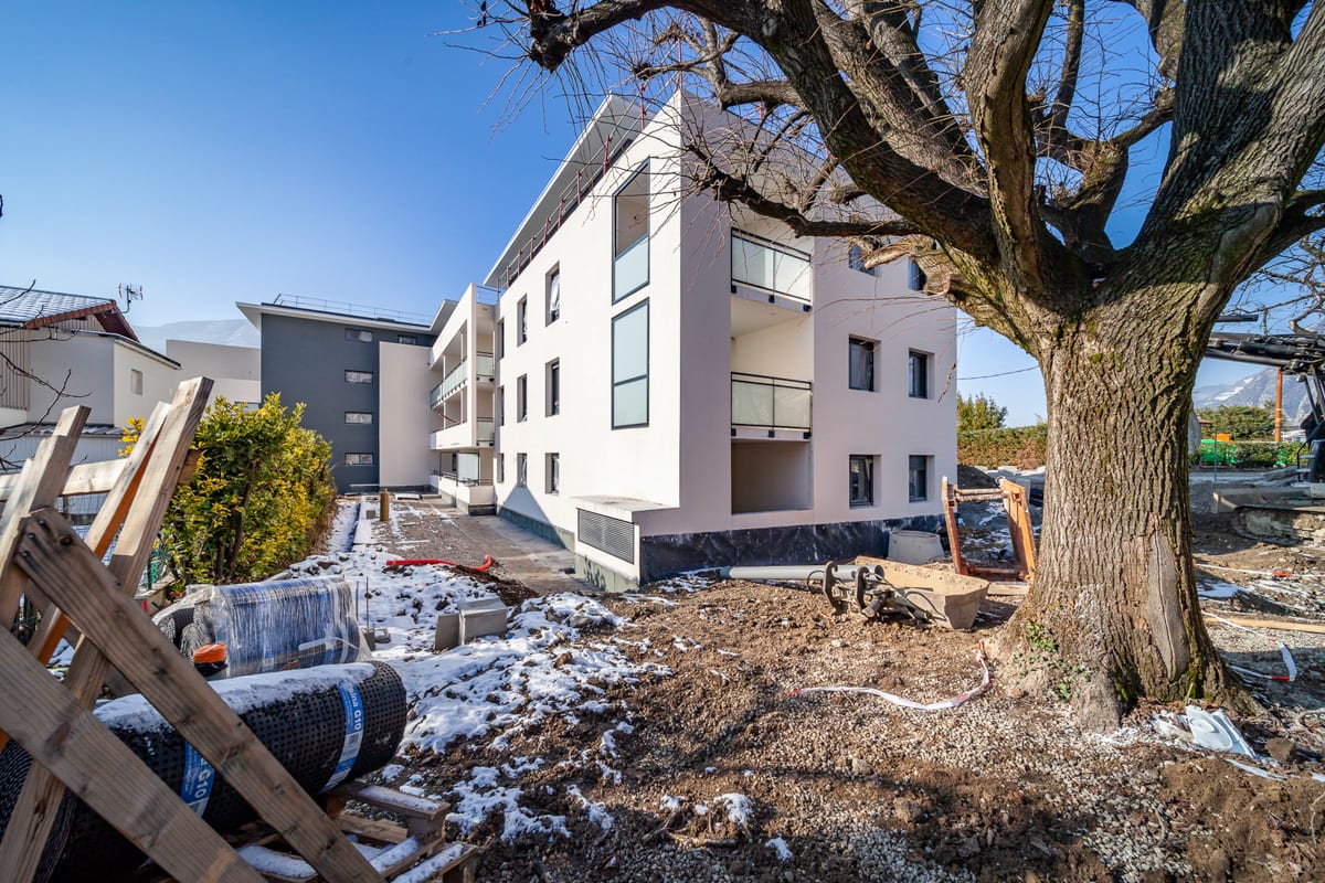 C'est l'hiver. Chantier avec vue sur le pignon d'un immeuble blanc et d'un arbre