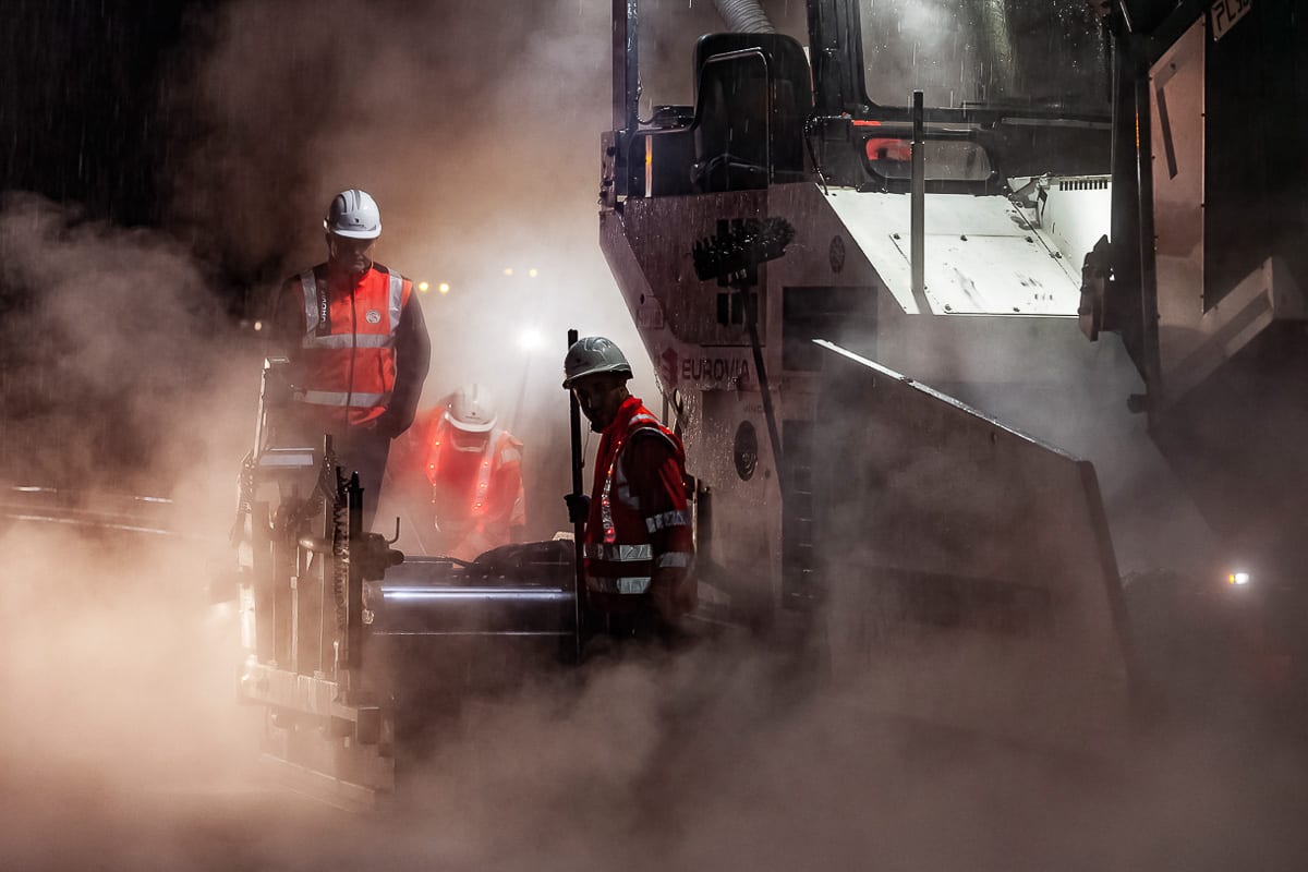 Trois ouvriers dans la vapeur d'un finisseur